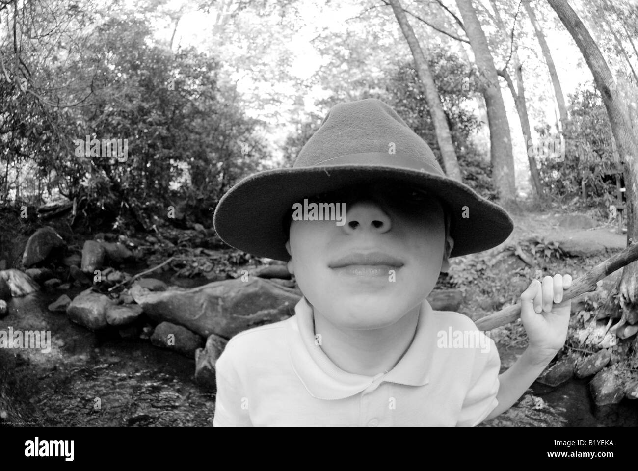 black and white of young boy looking under the rim of a hat, wide angle ...