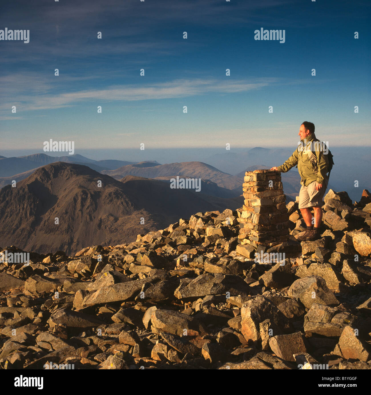 Walker on summit of Scafell, with Great Gable to left, Lake District National Park, Cumbria, UK, late afternoon Stock Photo