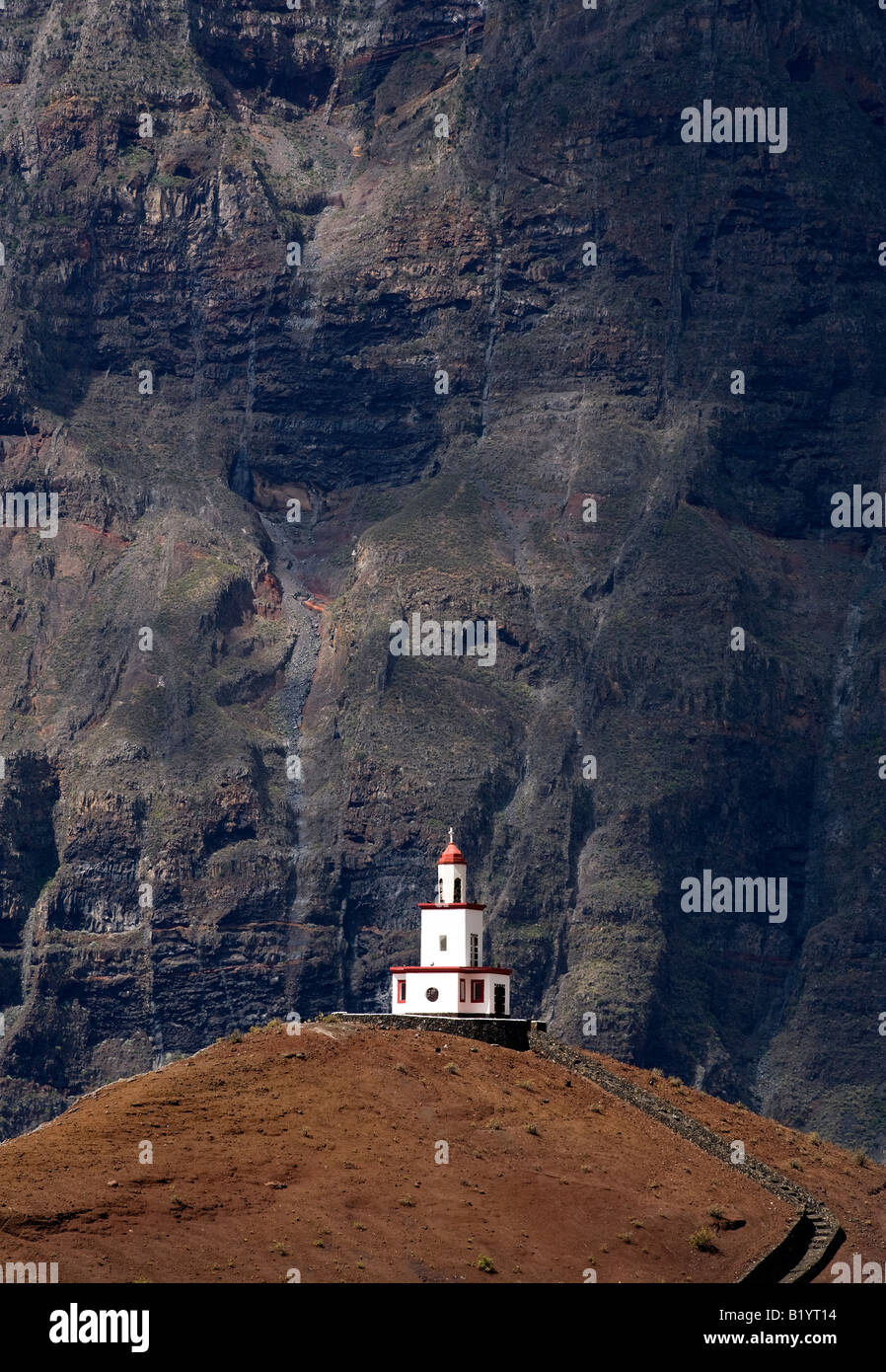 Bell tower of Ermita de la Caridad on a volcanic hill at El Hierro, Canary Islands, against harsh cliffs Stock Photo