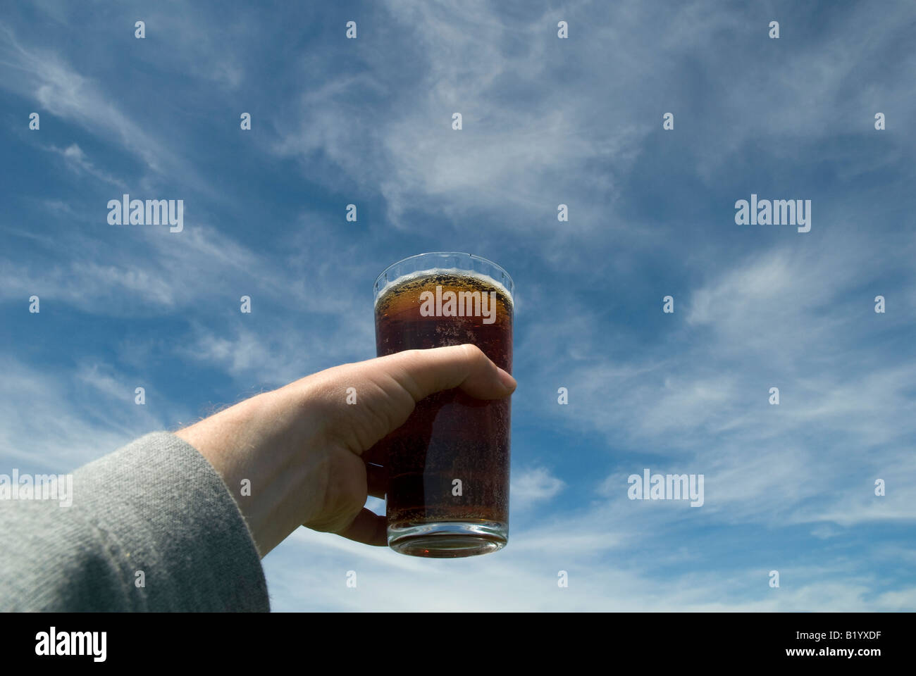 Holding up a pint of bitter against a blue sky Stock Photo