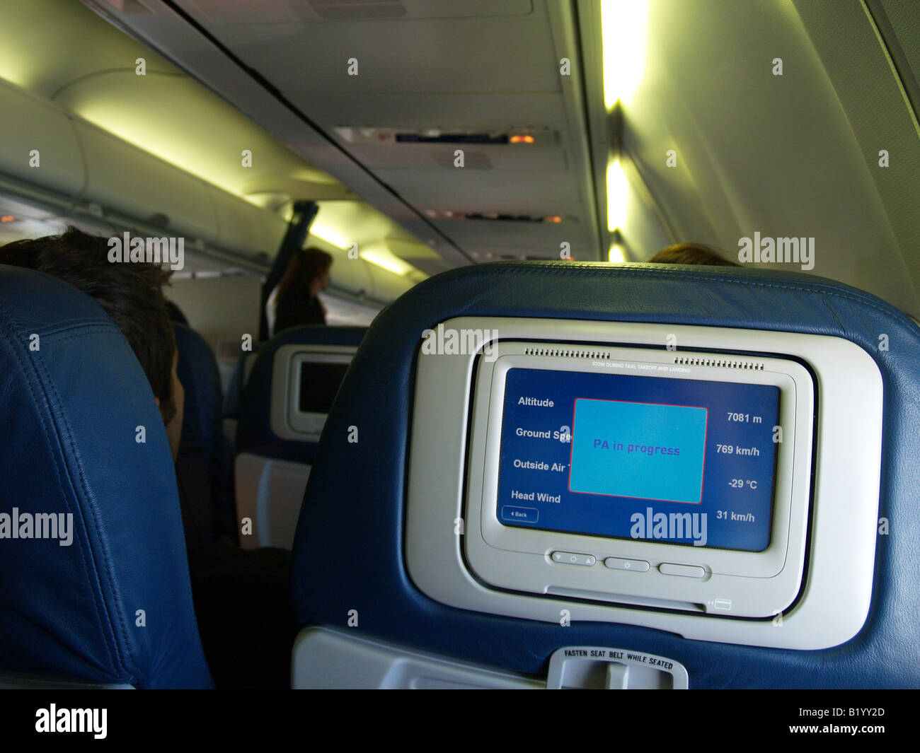 Cabin of in flight passenger airplane with flight specs showing on