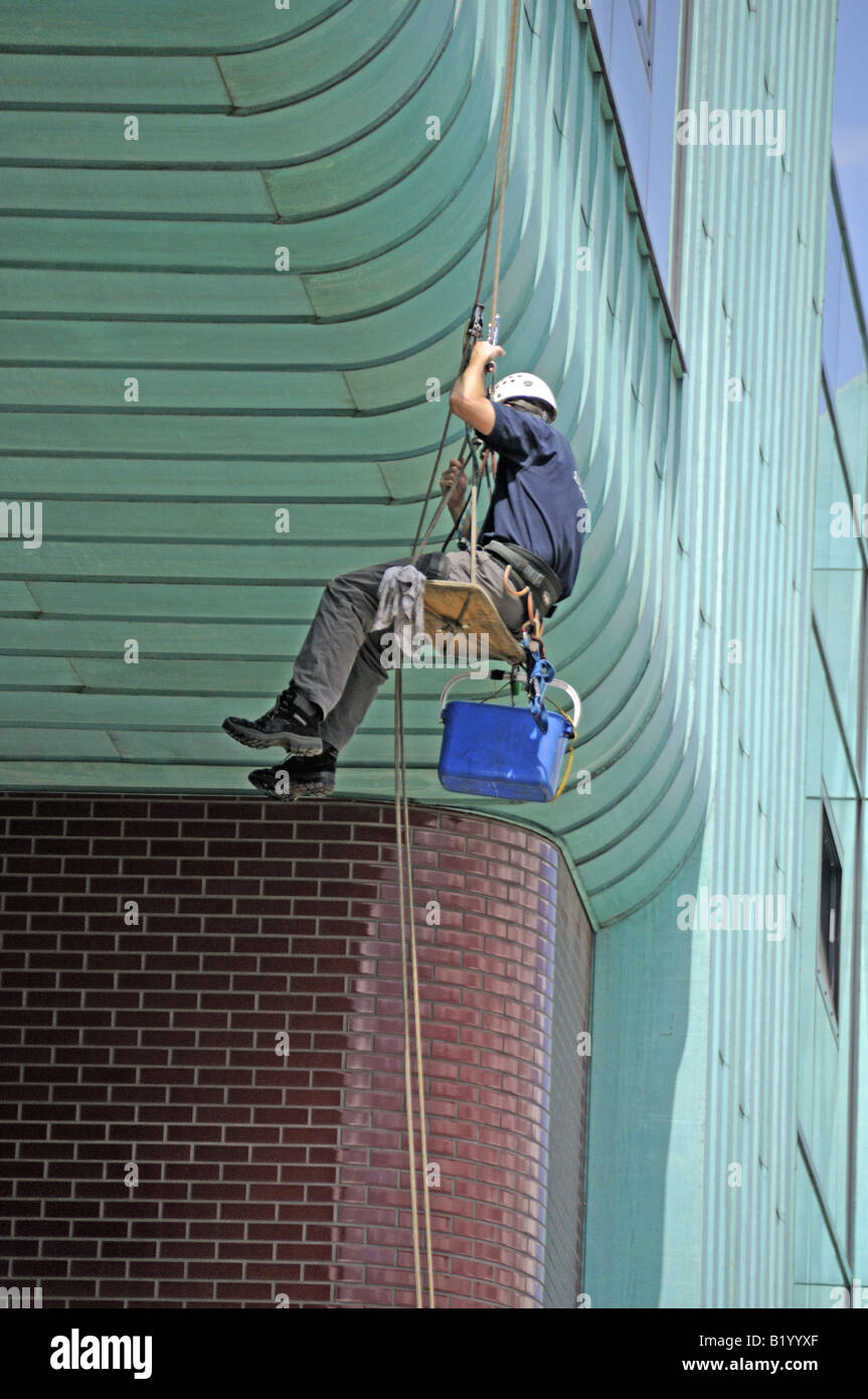 Window cleaner abseiling down the front of Arsenal s Stadium Highbury London England UK Stock Photo