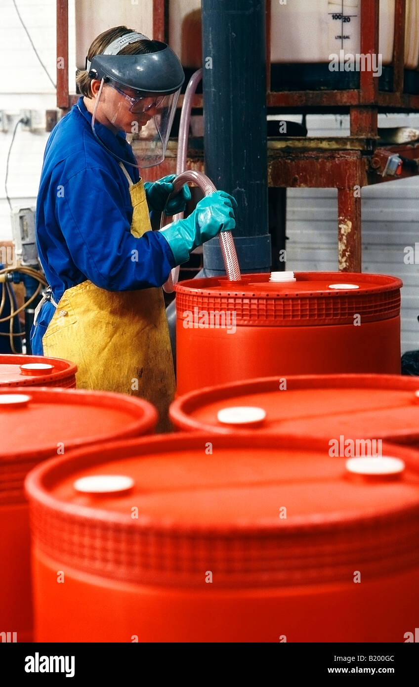 Chemical manufacturing worker filling 45 gallon drums with industrial