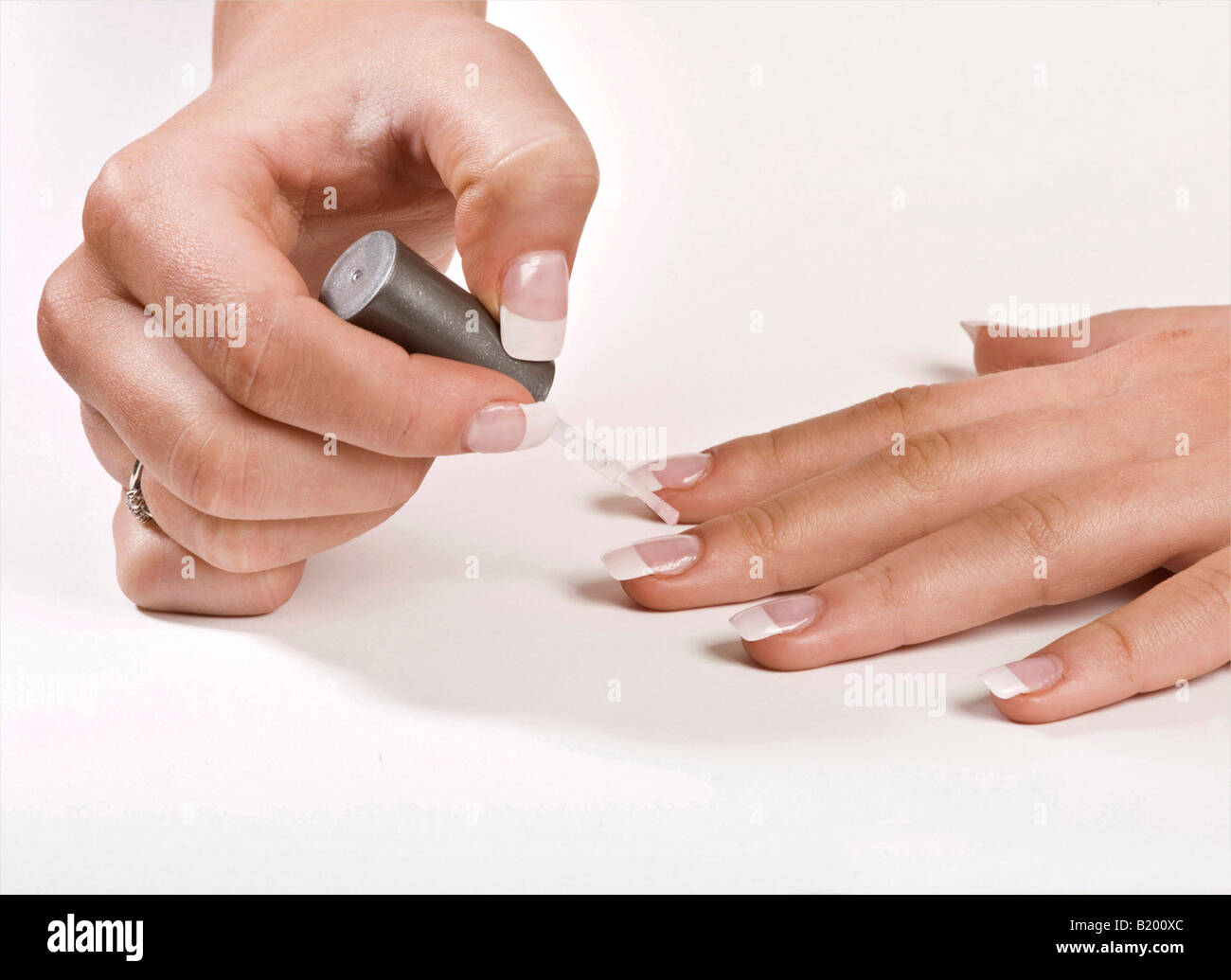 Close up of a ladies hands applying clear nail varnish to her false nails  Stock Photo - Alamy