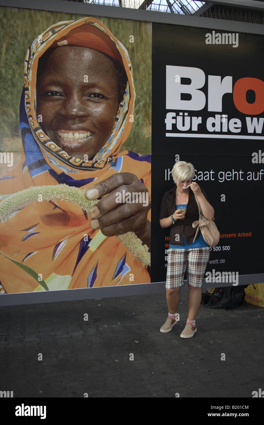 teenage girl eating in front of African 'Brot fuer die Welt' poster against poverty. Photo by Willy Matheisl Stock Photo