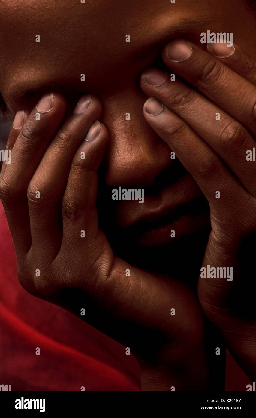 Sad black teenage boy portrait covering face with hands Stock Photo