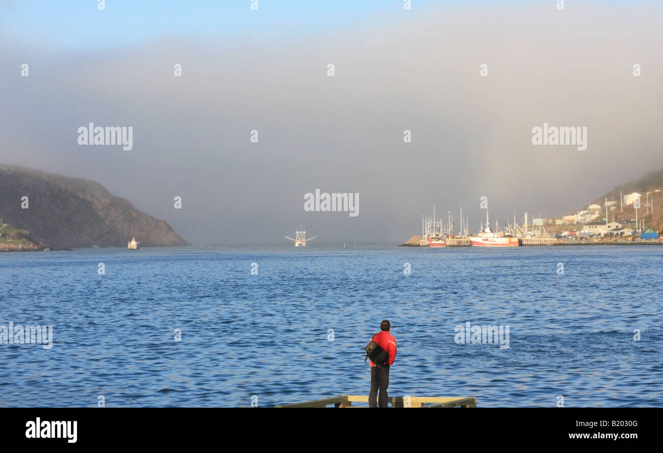 Heavy fog on St. John's Harbour with a lone man at dock Stock Photo