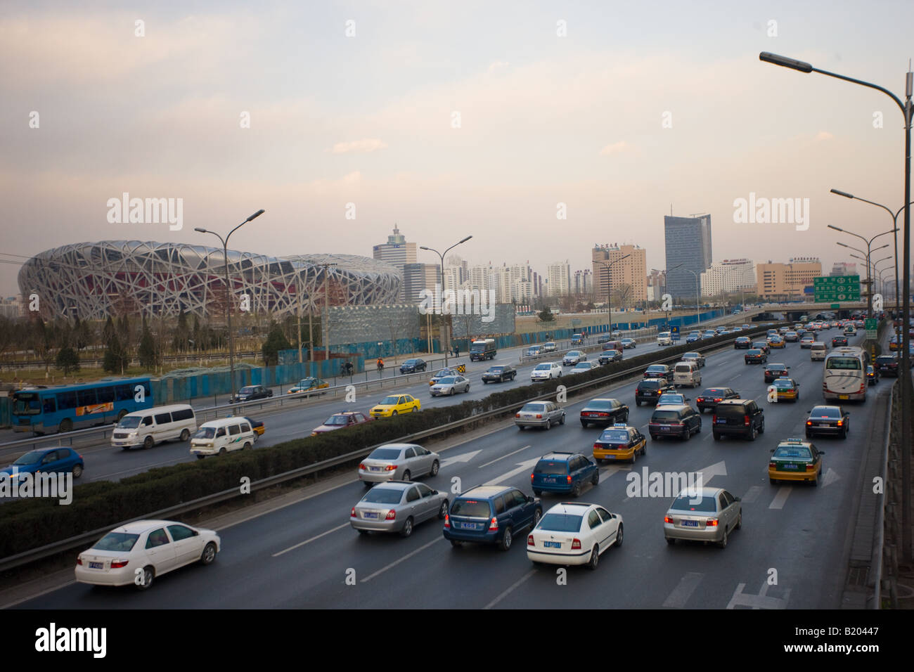 Traffic on motorway passes Olympics site of The Beijing National Stadium Bird s Nest China Stock Photo