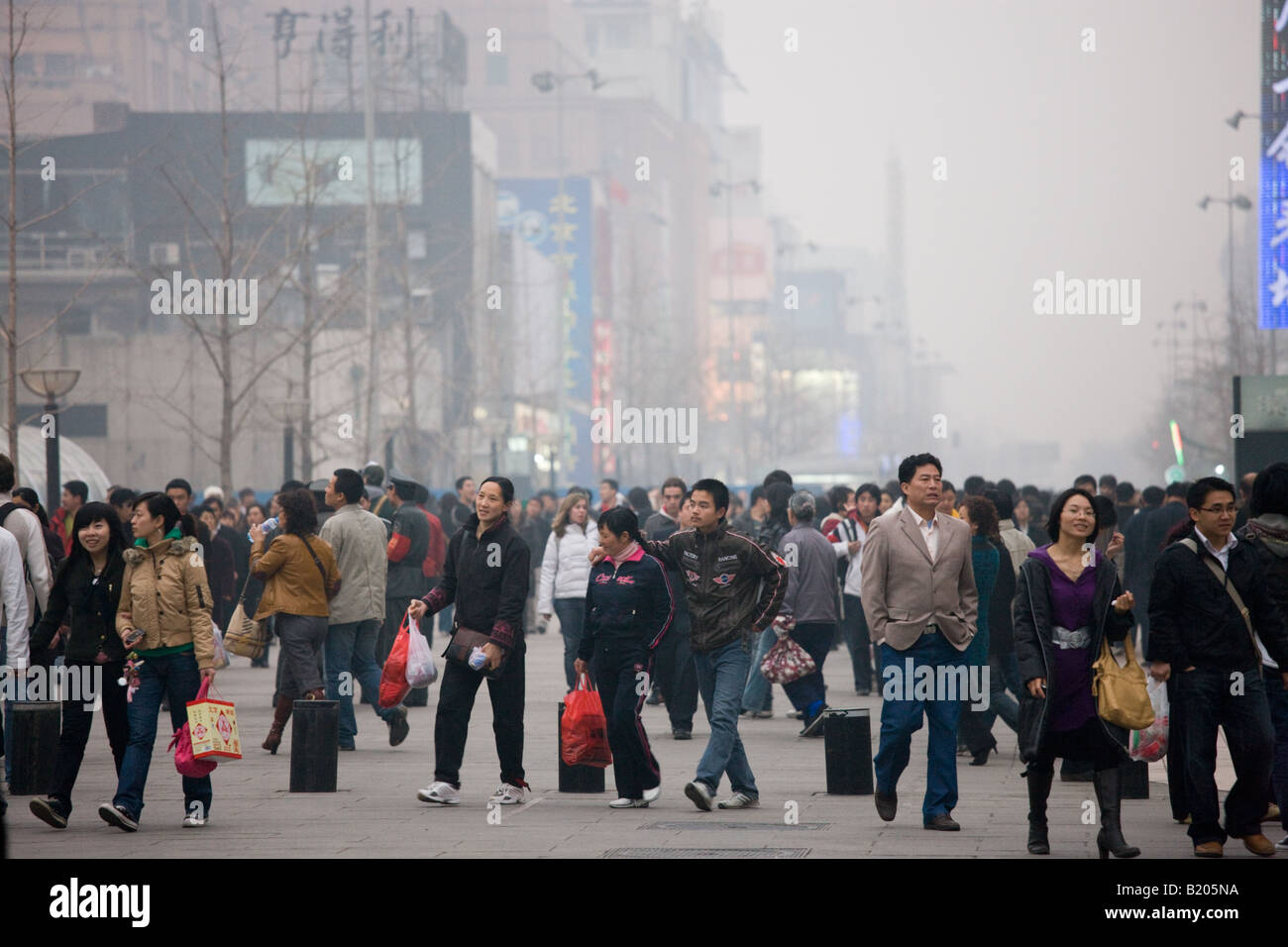Pedestrians crowded Wangfujing street and shops in smoggy Central Beijing China Stock Photo
