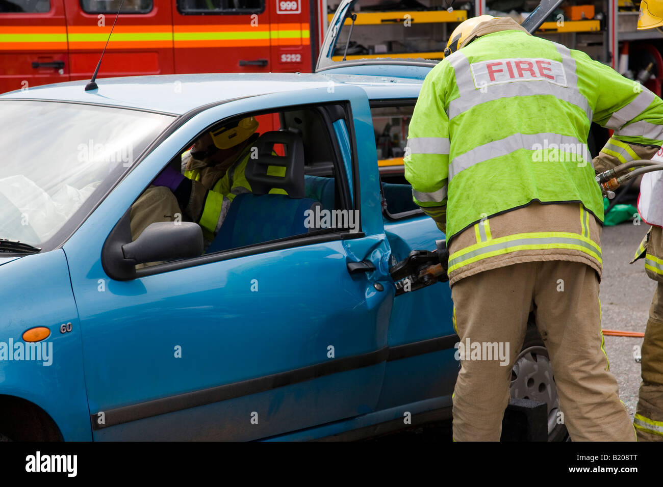 Firecrew using a specialised cutter to prise open a door on a crashed vehicle in a simulated demonstration, Surrey, England. Stock Photo