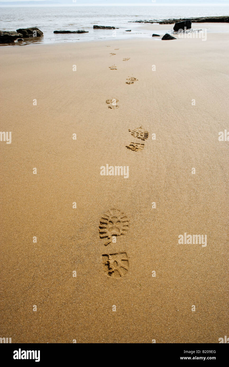 Footprints on beach leading out to sea. UK Stock Photo