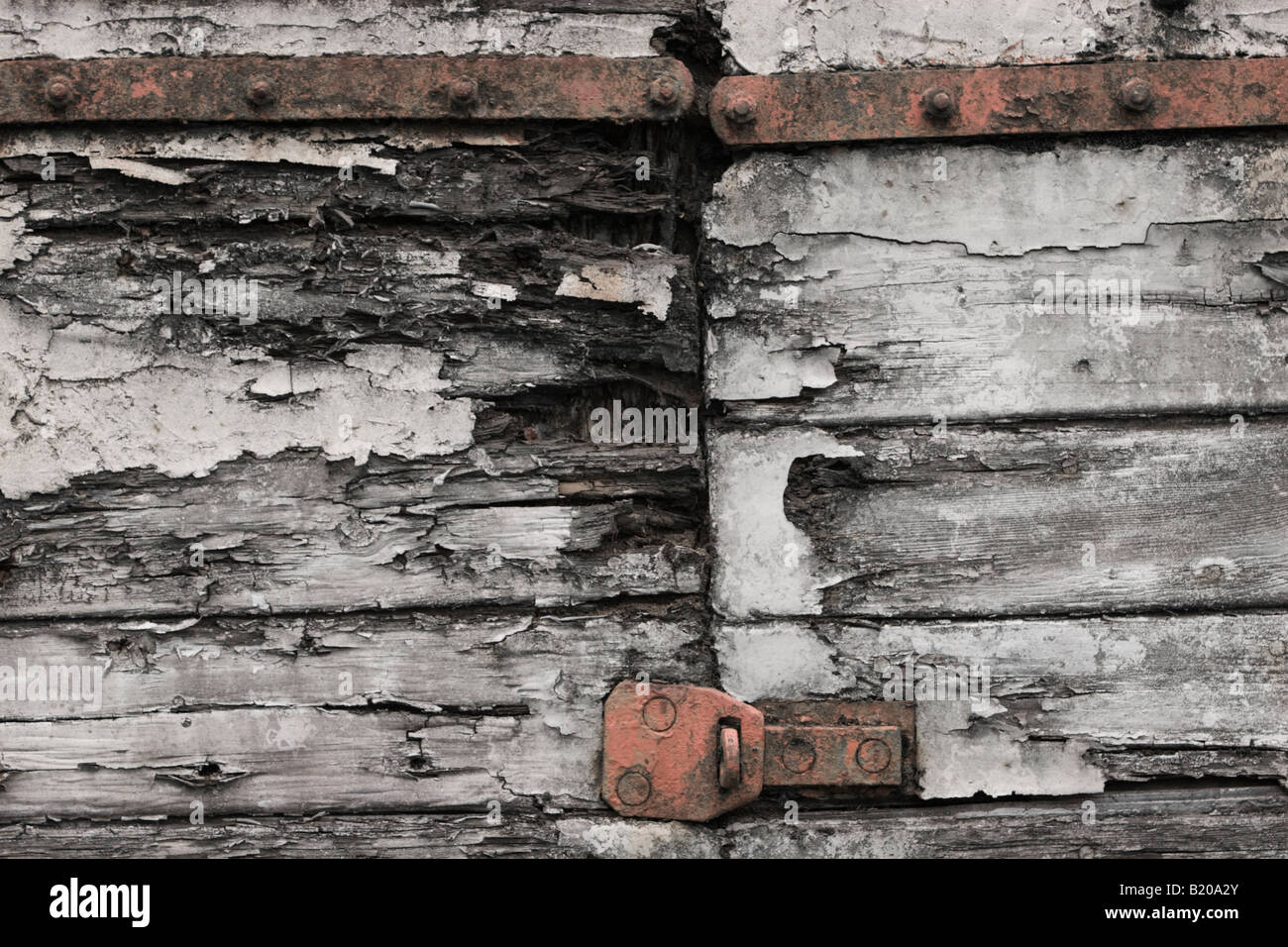 Flaking paint on rotting wood with rusting hinges Stock Photo