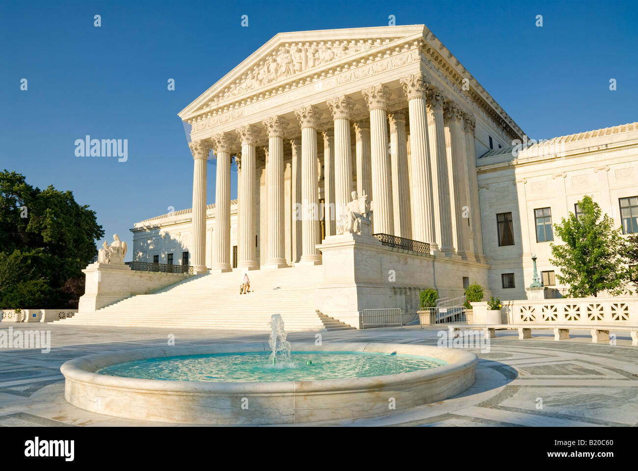 Supreme Court Building Fountain Washington DC // WASHINGTON DC — The United States Supreme Court building stands behind its iconic fountain on Capitol Hill in Washington, DC. The neoclassical building, completed in 1935, serves as the seat of the judicial branch of the U.S. federal government. The white marble structure, designed by architect Cass Gilbert, features the inscription 'Equal Justice Under Law' above its main entrance. The building houses the courtroom where the nine justices hear cases, as well as offices and the Supreme Court Library. Stock Photo