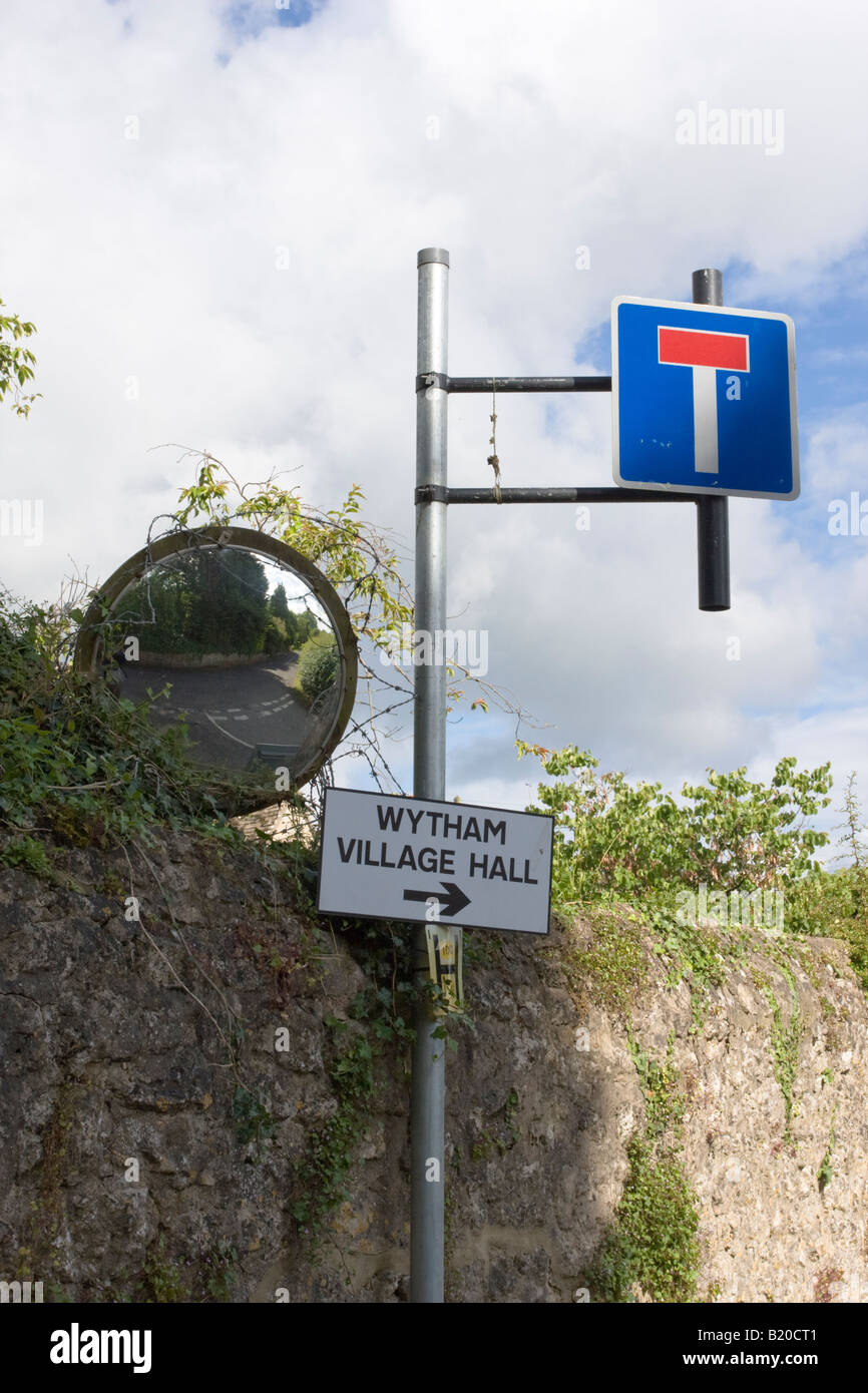 A Concave mirror shows a road junction No Through Road sign and Village Hall sign Wytham Oxfordshire Stock Photo