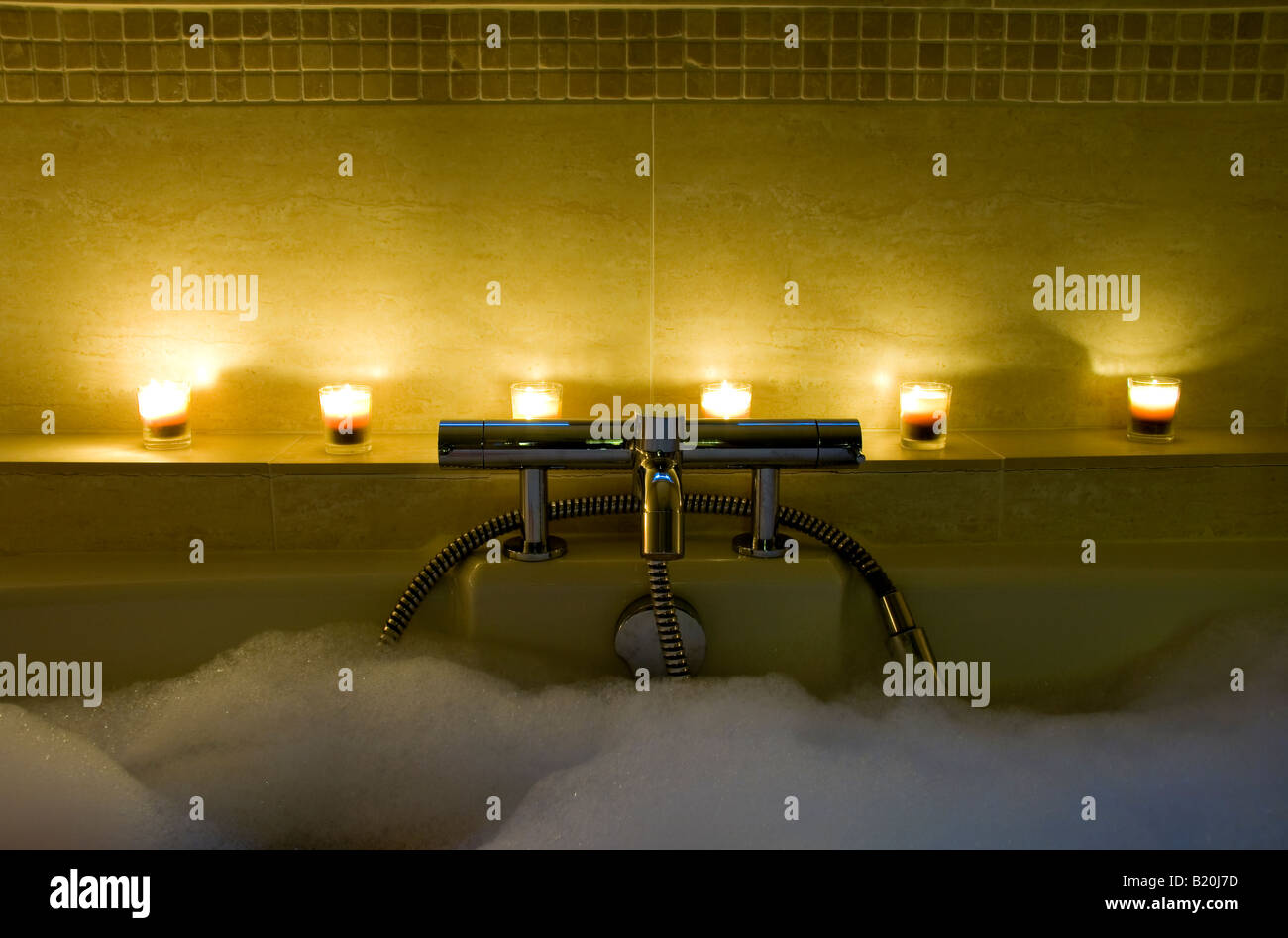 6 candles on a shelf behind a bath's taps Stock Photo