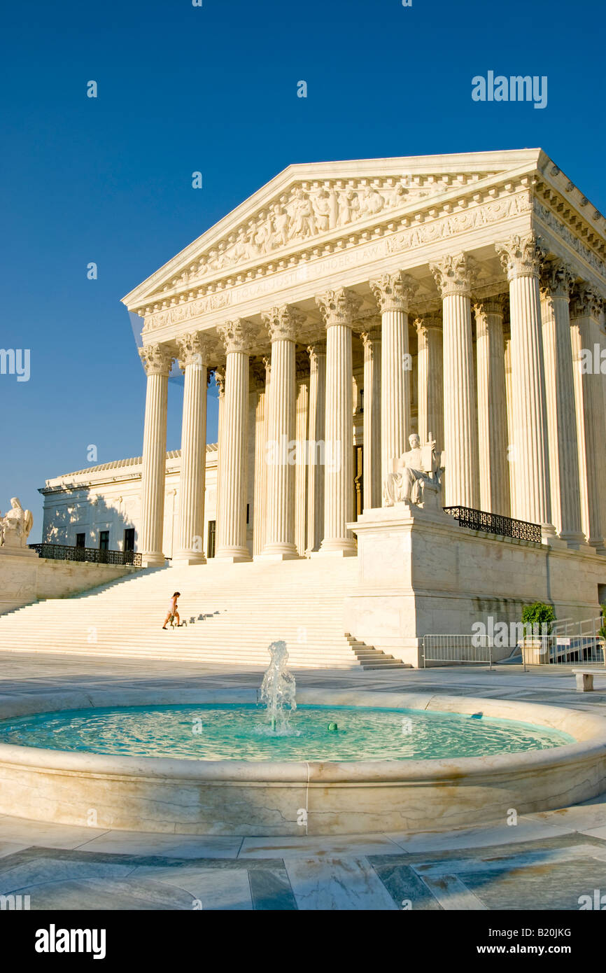 Supreme Court Building Fountain Washington DC // WASHINGTON DC — The United States Supreme Court building stands behind its iconic fountain on Capitol Hill in Washington, DC. The neoclassical building, completed in 1935, serves as the seat of the judicial branch of the U.S. federal government. The white marble structure, designed by architect Cass Gilbert, features the inscription 'Equal Justice Under Law' above its main entrance. The building houses the courtroom where the nine justices hear cases, as well as offices and the Supreme Court Library. Stock Photo
