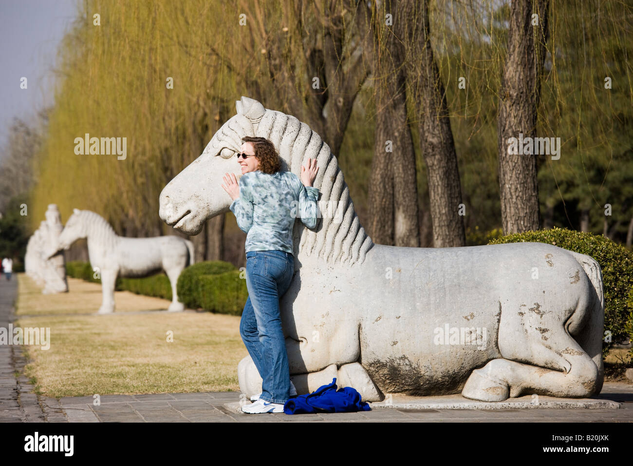 Tourist poses with statue of a resting horse Spirit Way Ming Tombs Changling Beijing China Stock Photo