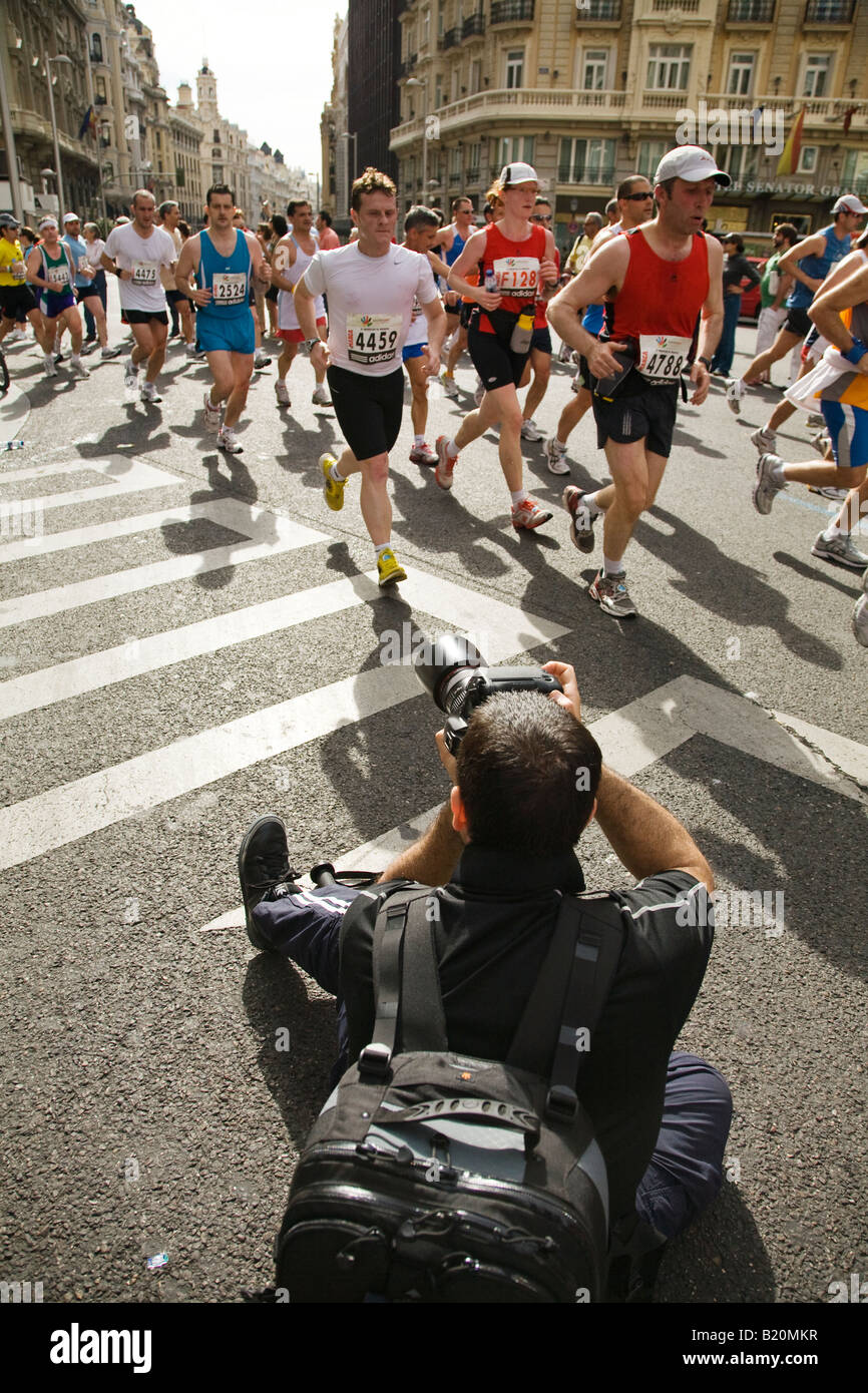 SPAIN Madrid Man wear backpack and sit in street to photograph runners in marathon race on Gran Via Street Stock Photo