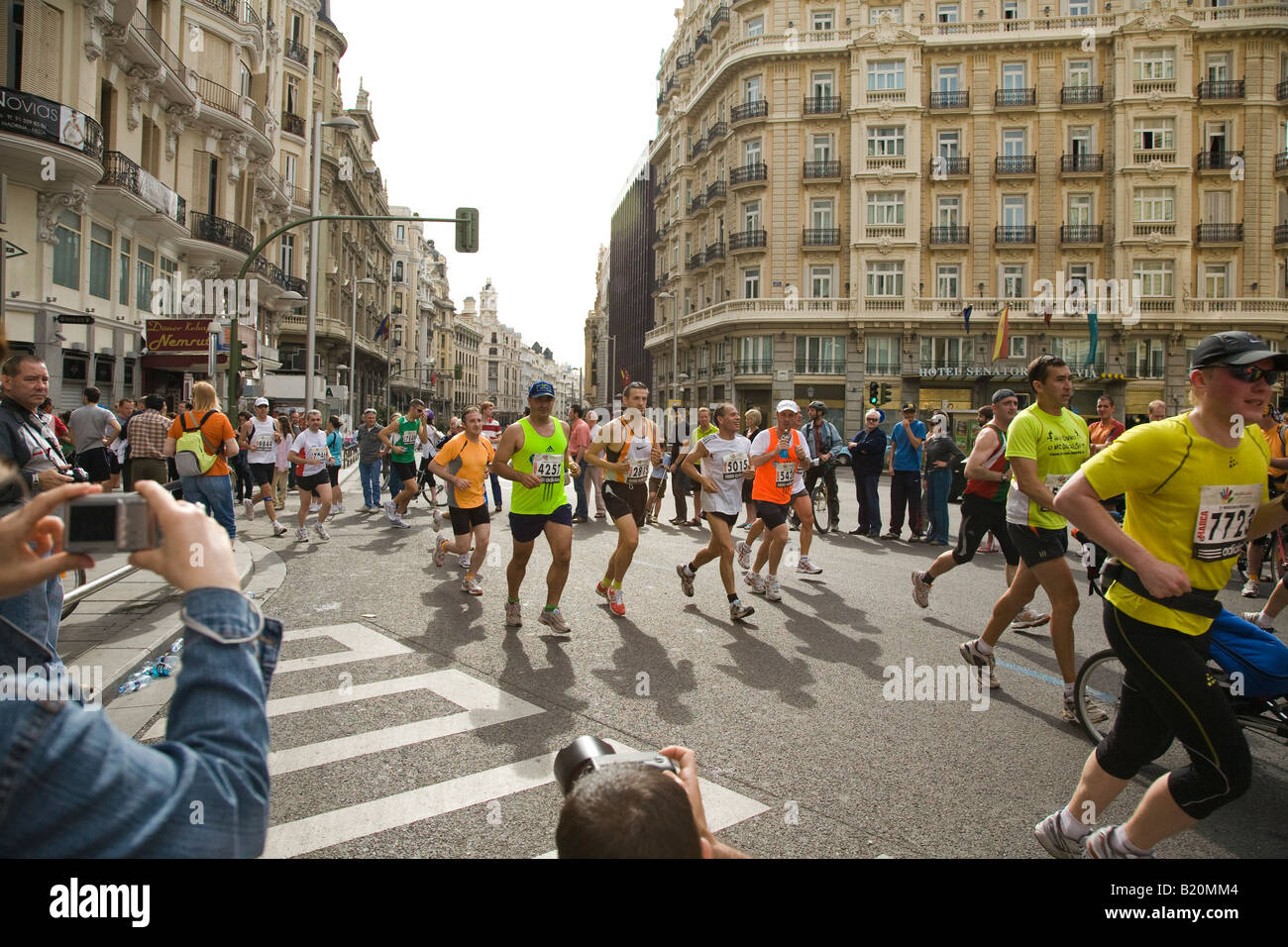 SPAIN Madrid Photographers stand and sit in street to photograph runners in marathon race on Gran Via Street Stock Photo