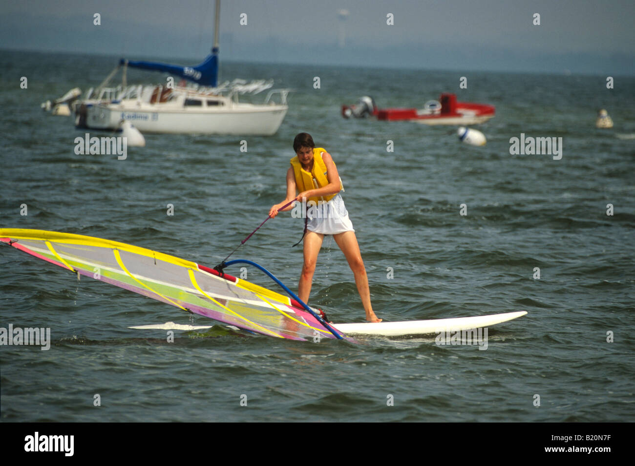 WINDSURF Madison Wisconsin Female college student learning to windsurf pulling up sail out of water on Lake Mendota Stock Photo