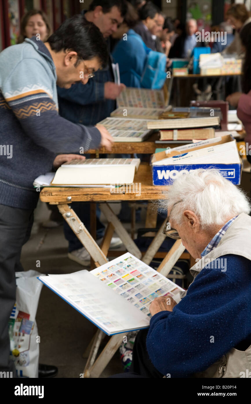 SPAIN Madrid Stamp collectors trade and sell collections in Plaza Mayor on Sunday morning Look through notebooks Stock Photo