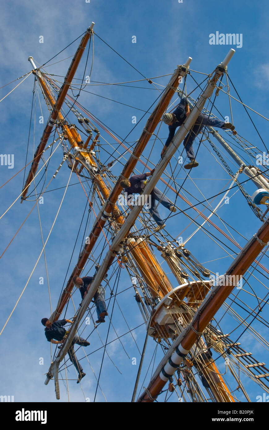 Crew of the tall ship Windeward Bound bending a new sail on to a