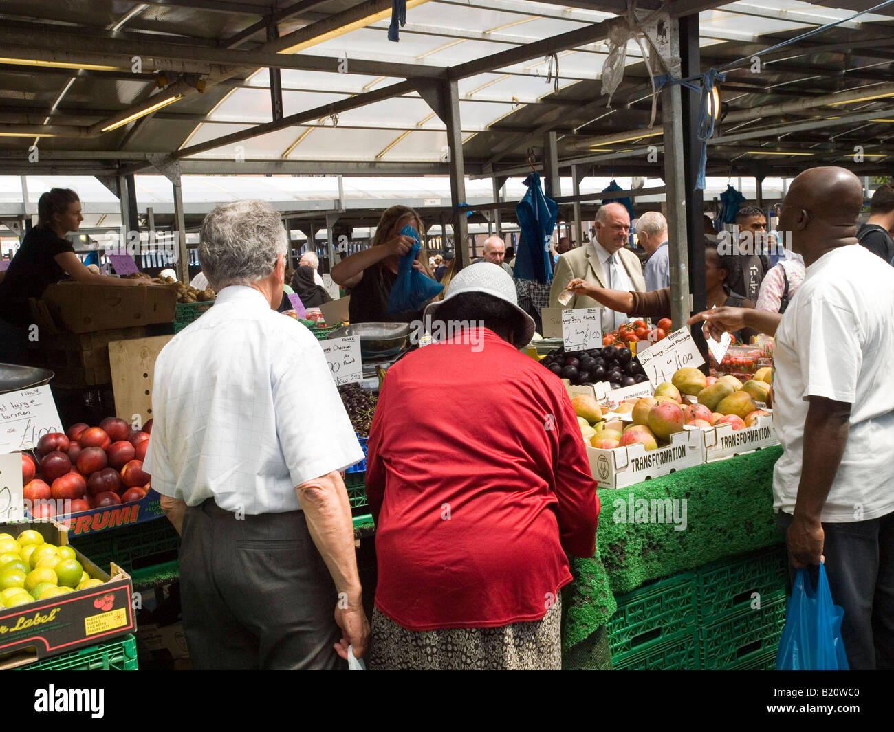 People buying from a fruit and vegetable stall in the Bull Ring Market ...