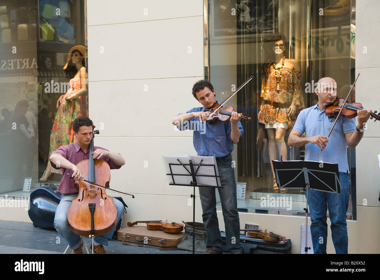 SPAIN Madrid Three male musicians playing cello and violins in front of