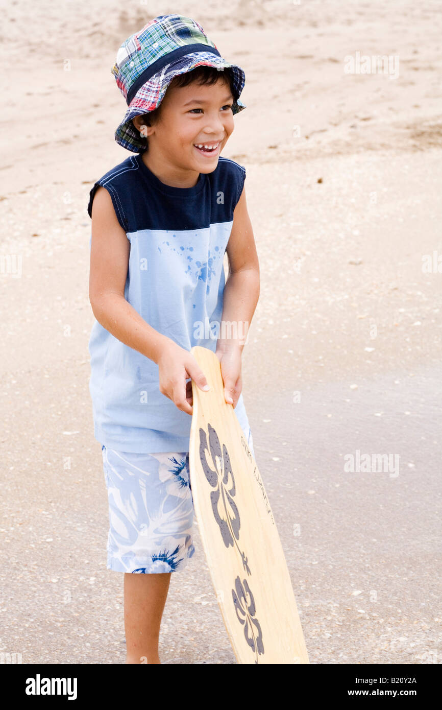 Young boy 5 6 years old looking away holding a skim board on the
