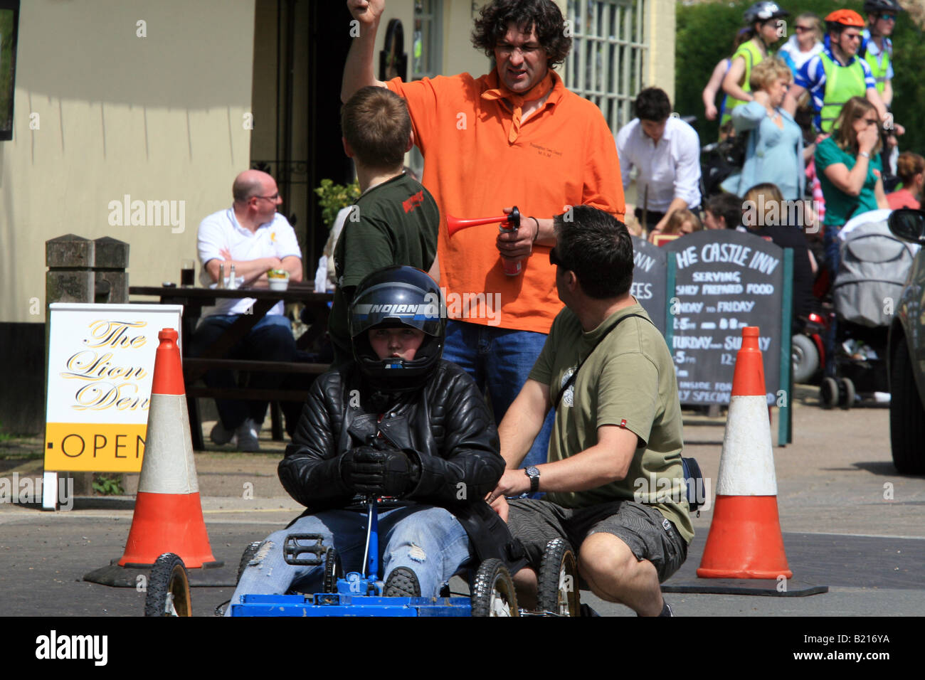 Soapbox with driver and two pushers waits with a race official at the start Stock Photo