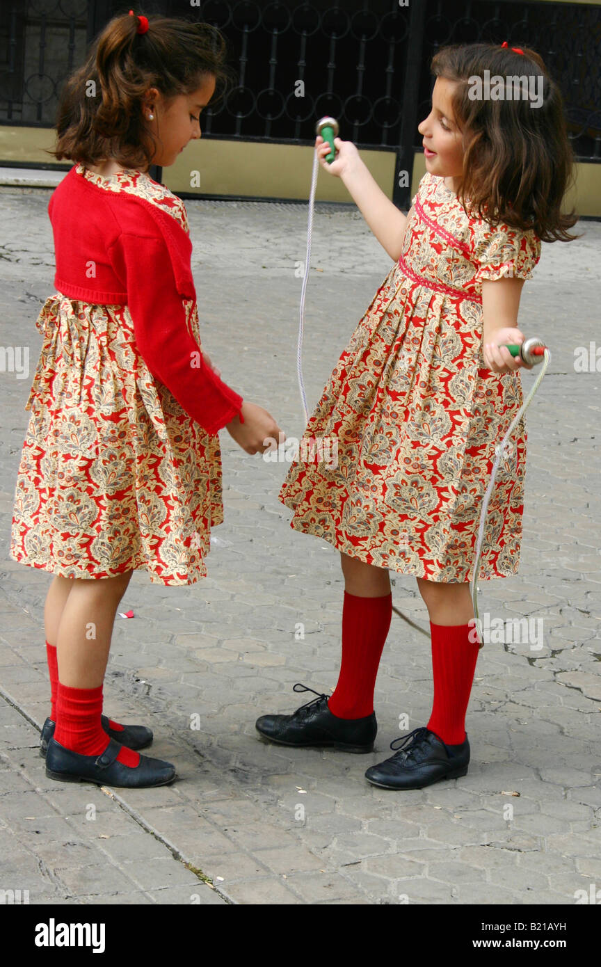Twin sisters in matching outfits skipping in Seville, Spain Stock Photo