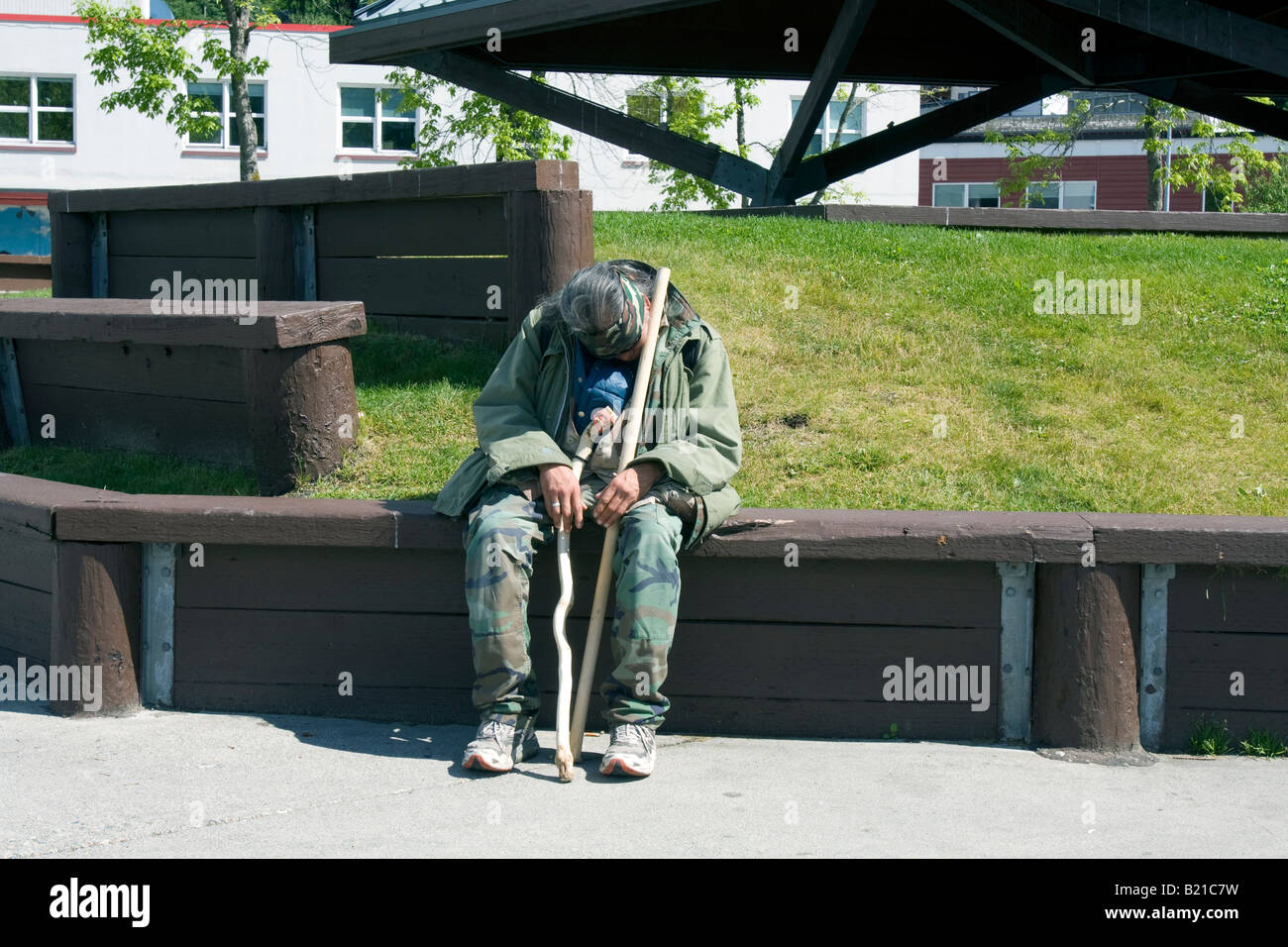 Homeless man sleeping sitting up right in a park in Juneau, Alaska, USA