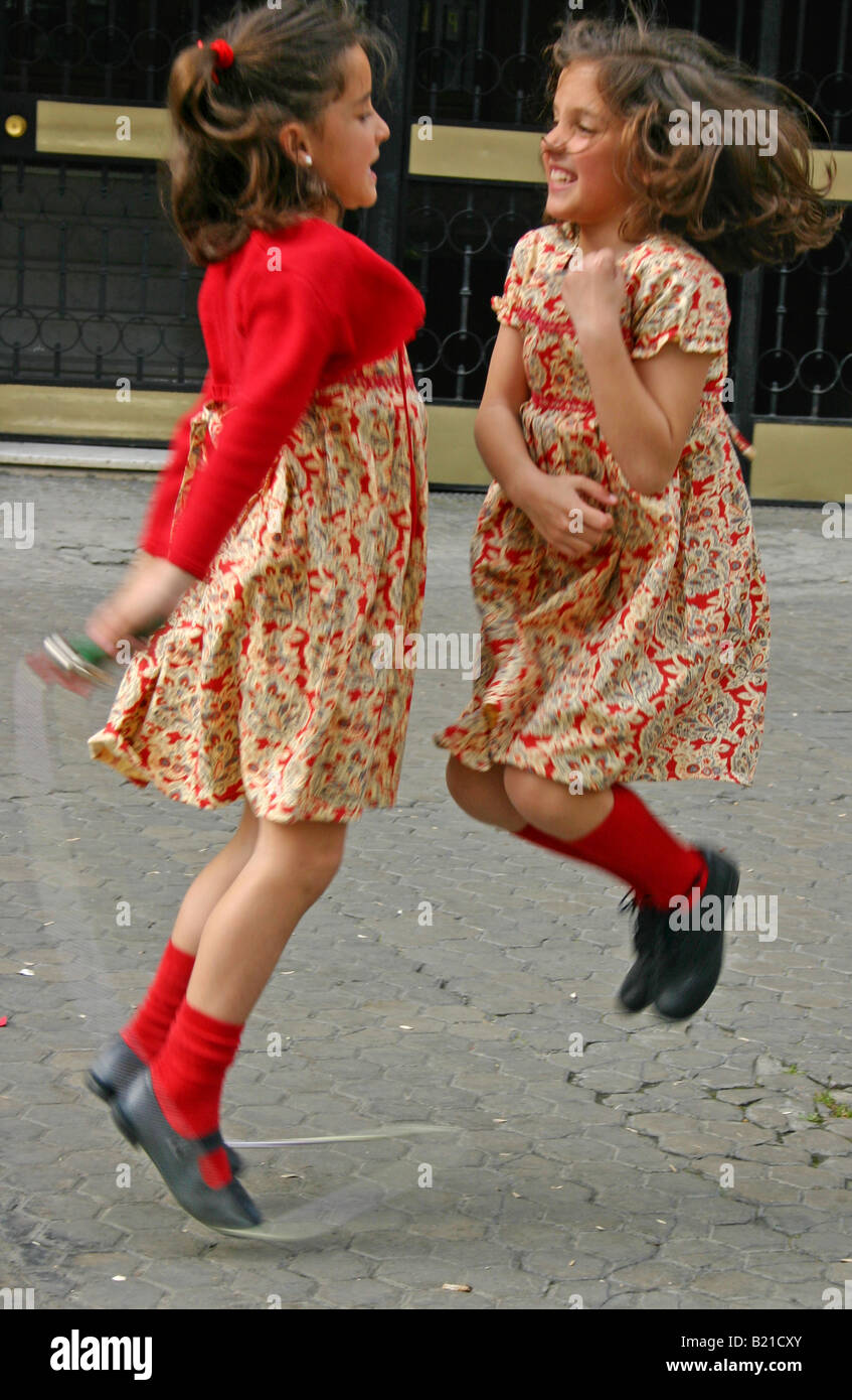 Twin sisters in matching outfits skipping in Seville, Spain Stock Photo