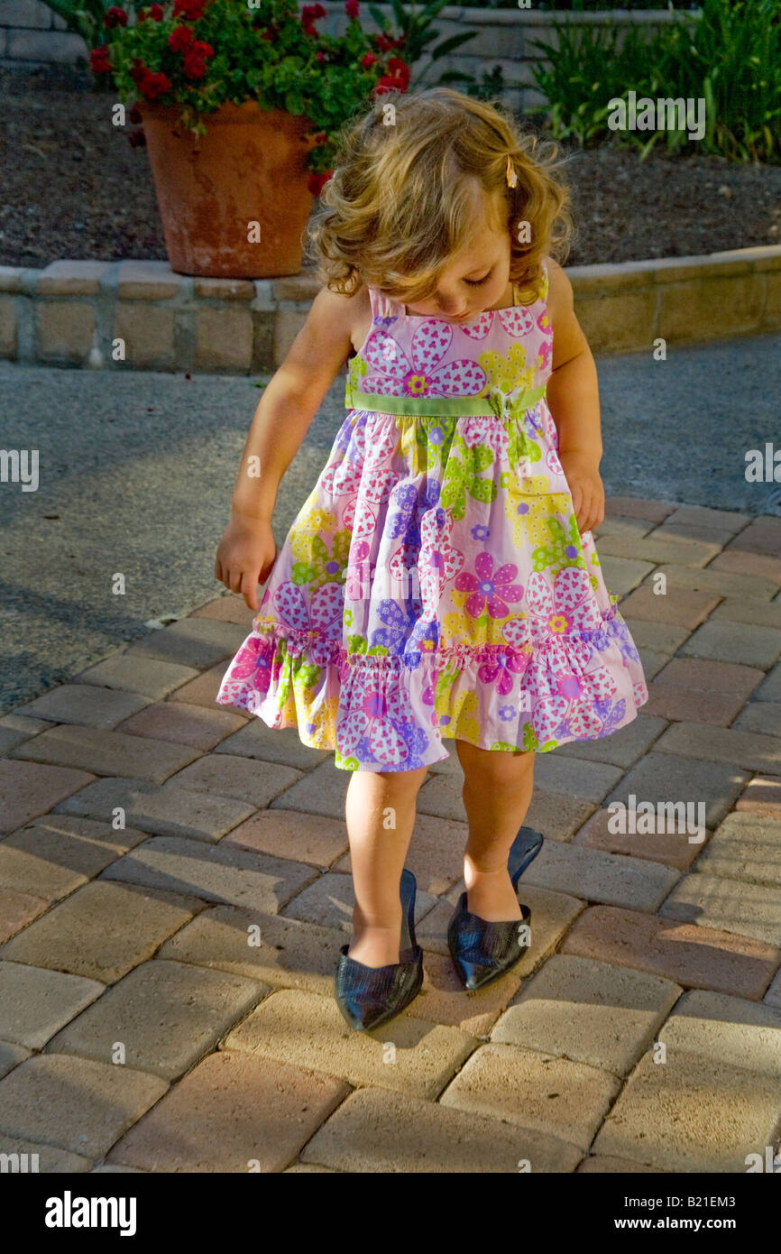 A two year old girl walks in her mother s shoes at home in Southern California Stock Photo