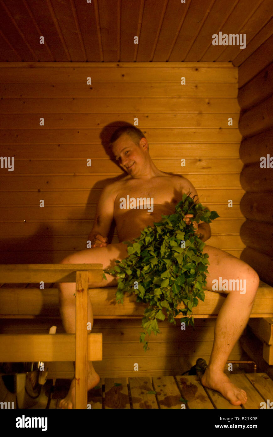 A crazy naked finn in Sauna, covering private parts with a traditional finnish sauna whisk Stock Photo