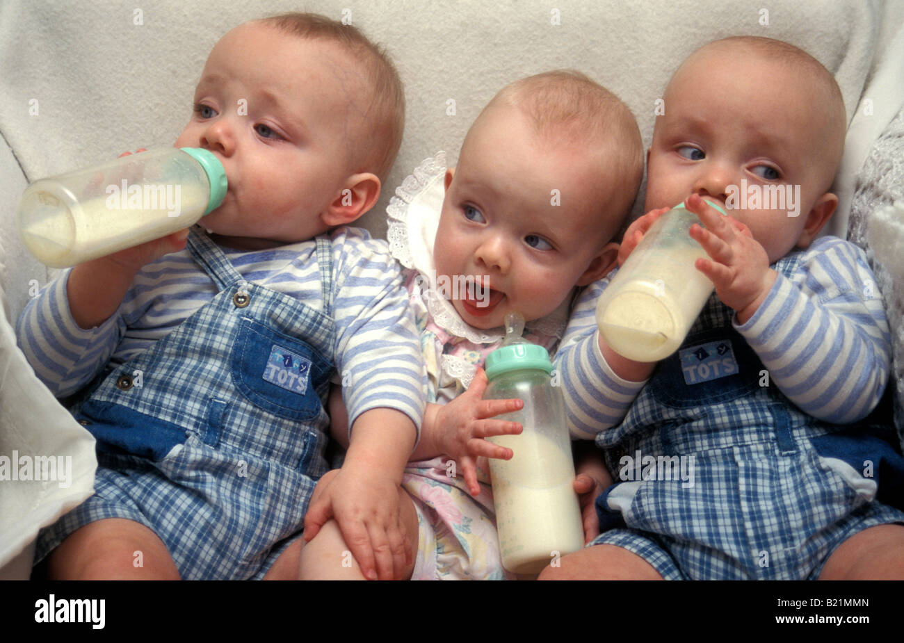 baby triplets drinking milk from bottles Stock Photo