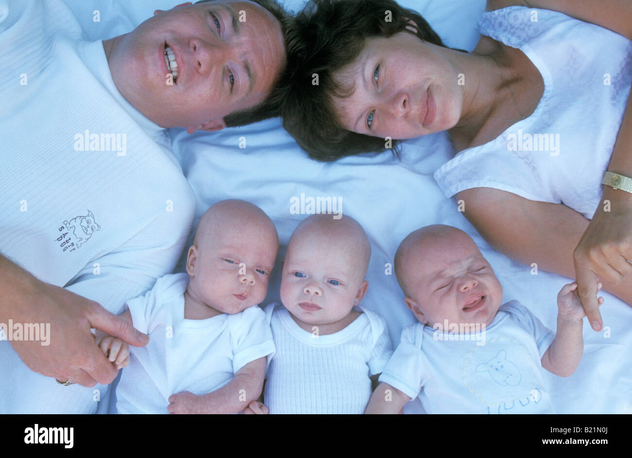 portrait couple with their baby triplets Stock Photo