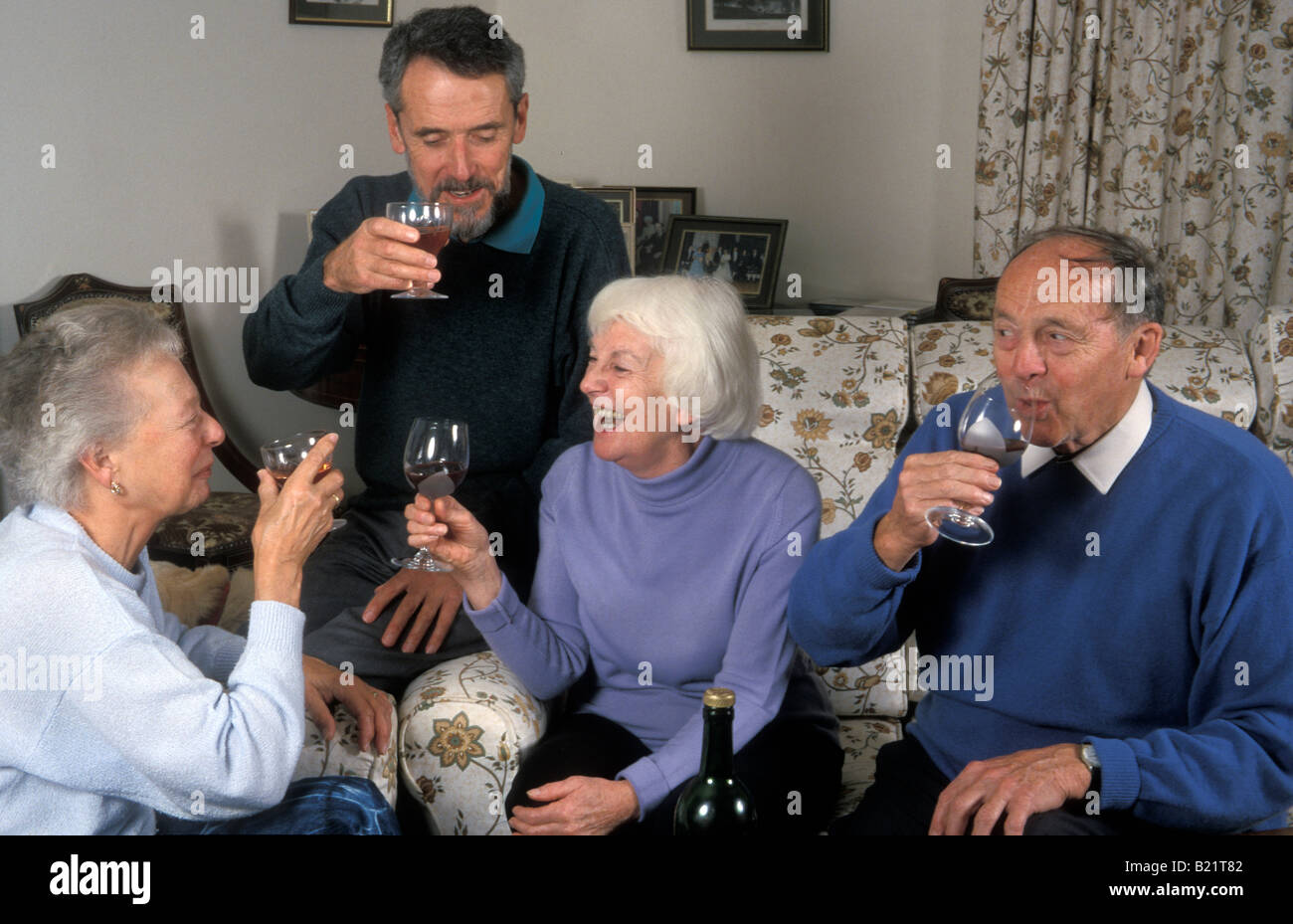 group of seniors drinking wine at home and having fun Stock Photo