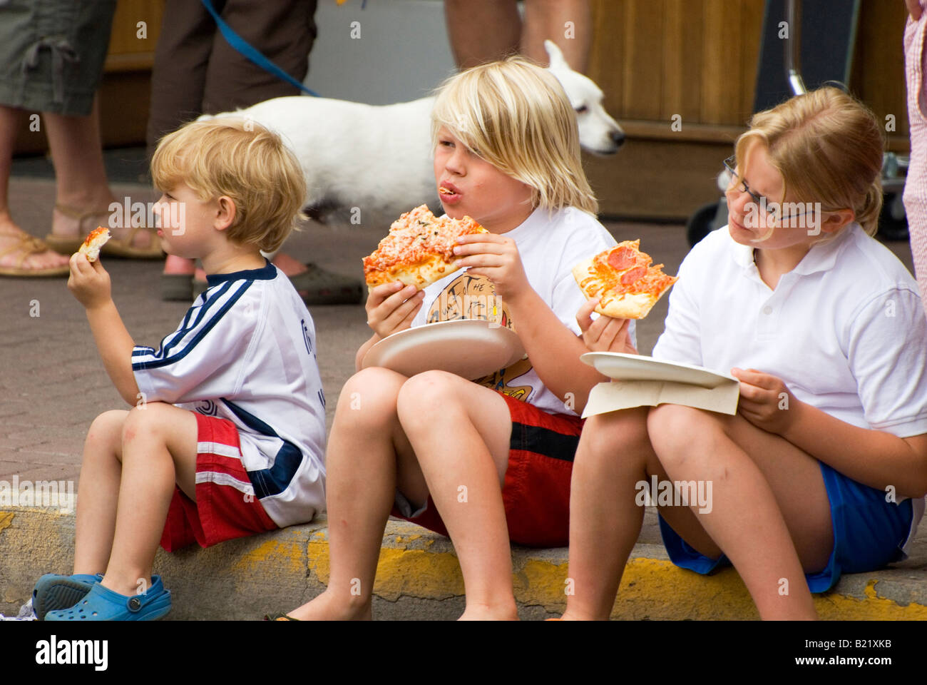 Children eating pizza watching 4th of July Parade Bend Oregon USA Stock