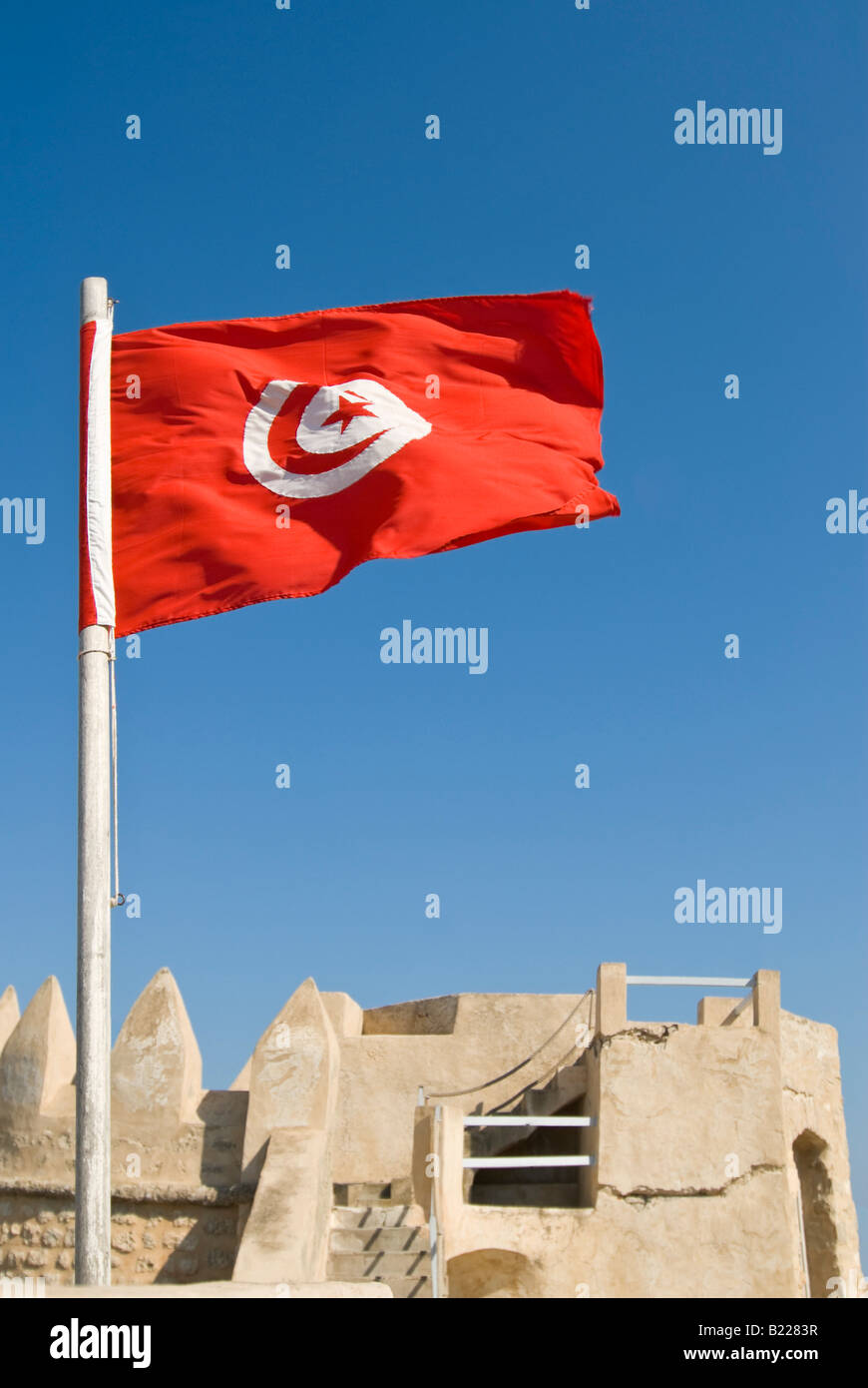 Vertical close up of the 'post 1999' Tunisian flag with red crescent and star against a blue sky Stock Photo