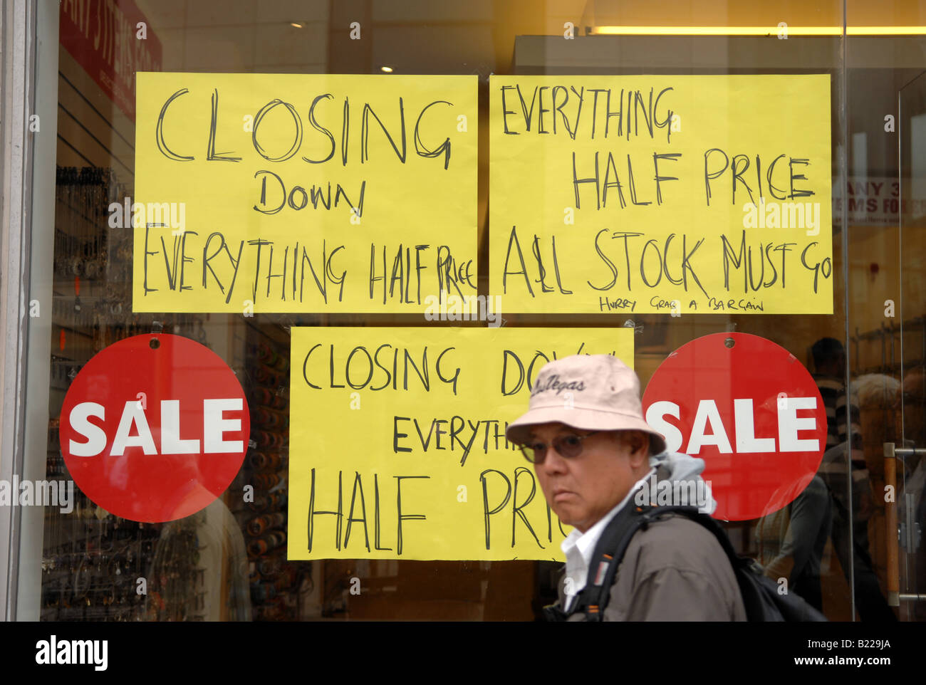 Shoppers walk past Closing Down Sale posters at a shop in Brighton UK