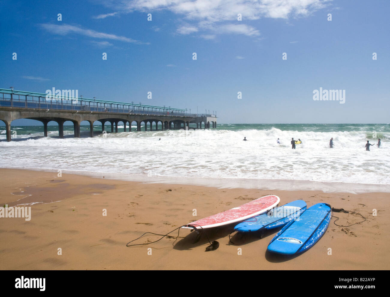 Surf boards on beach showing surfers and pier in the distance