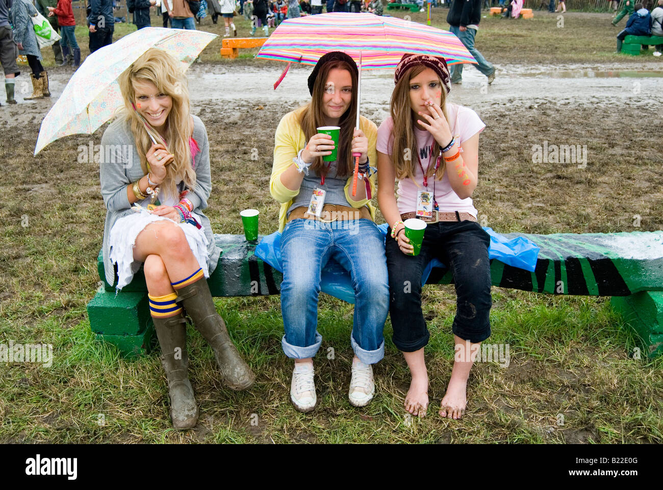 Three young woman drinking and smoking in the rain at Glastonbury festival Stock Photo