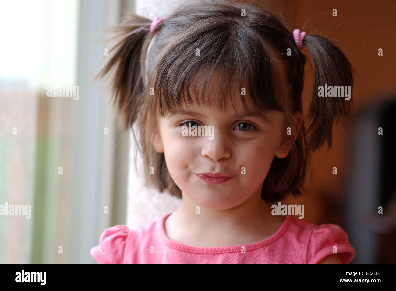 Pretty little girl by the window, looking at the camera Stock Photo - Alamy