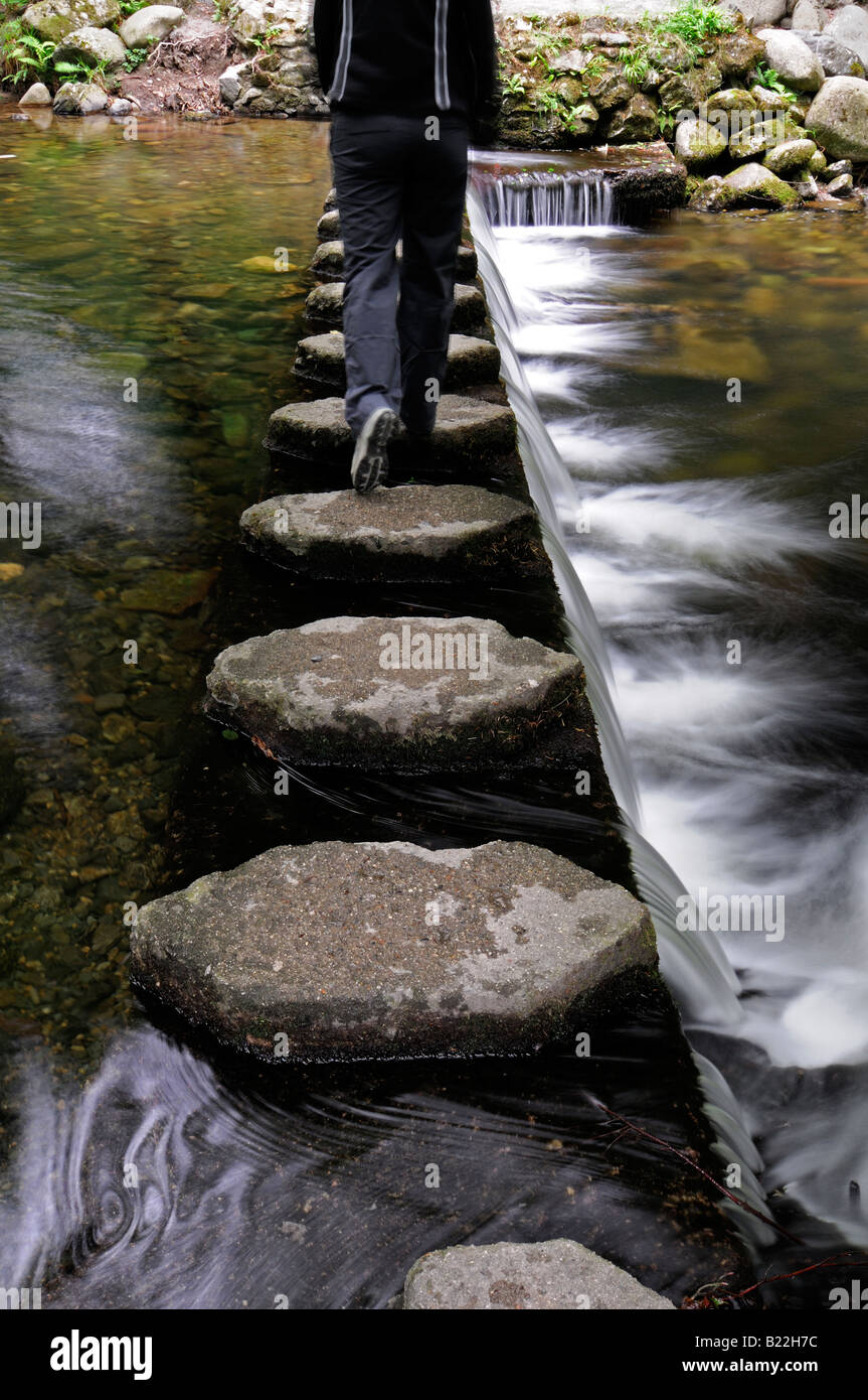 woman walking on stepping stones footpath walkway crossing cross across the shimna river tollymore county down northern ireland Stock Photo