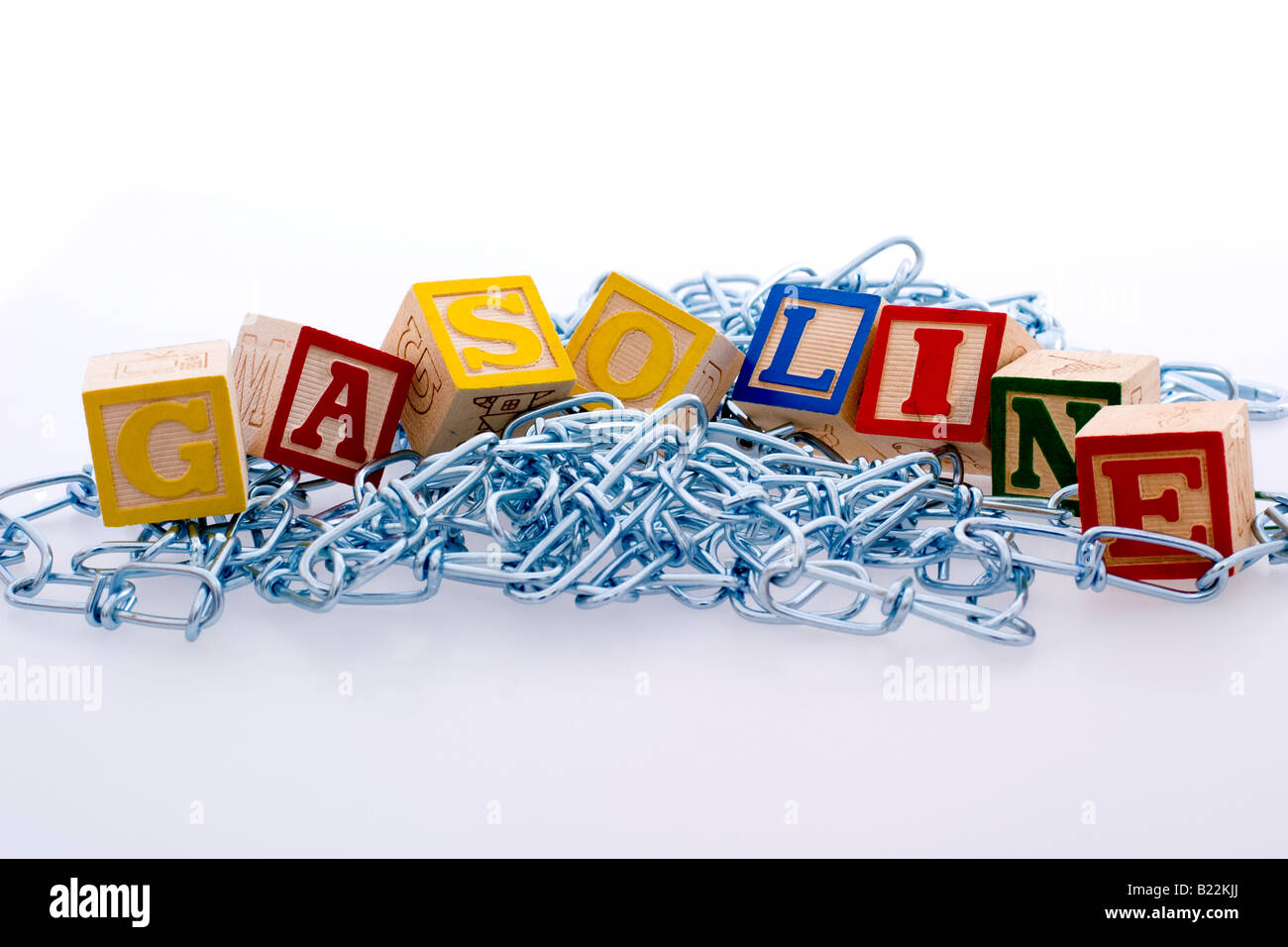 Children's blocks spelling out 'gasoline' atop a pile of metal chains Stock Photo
