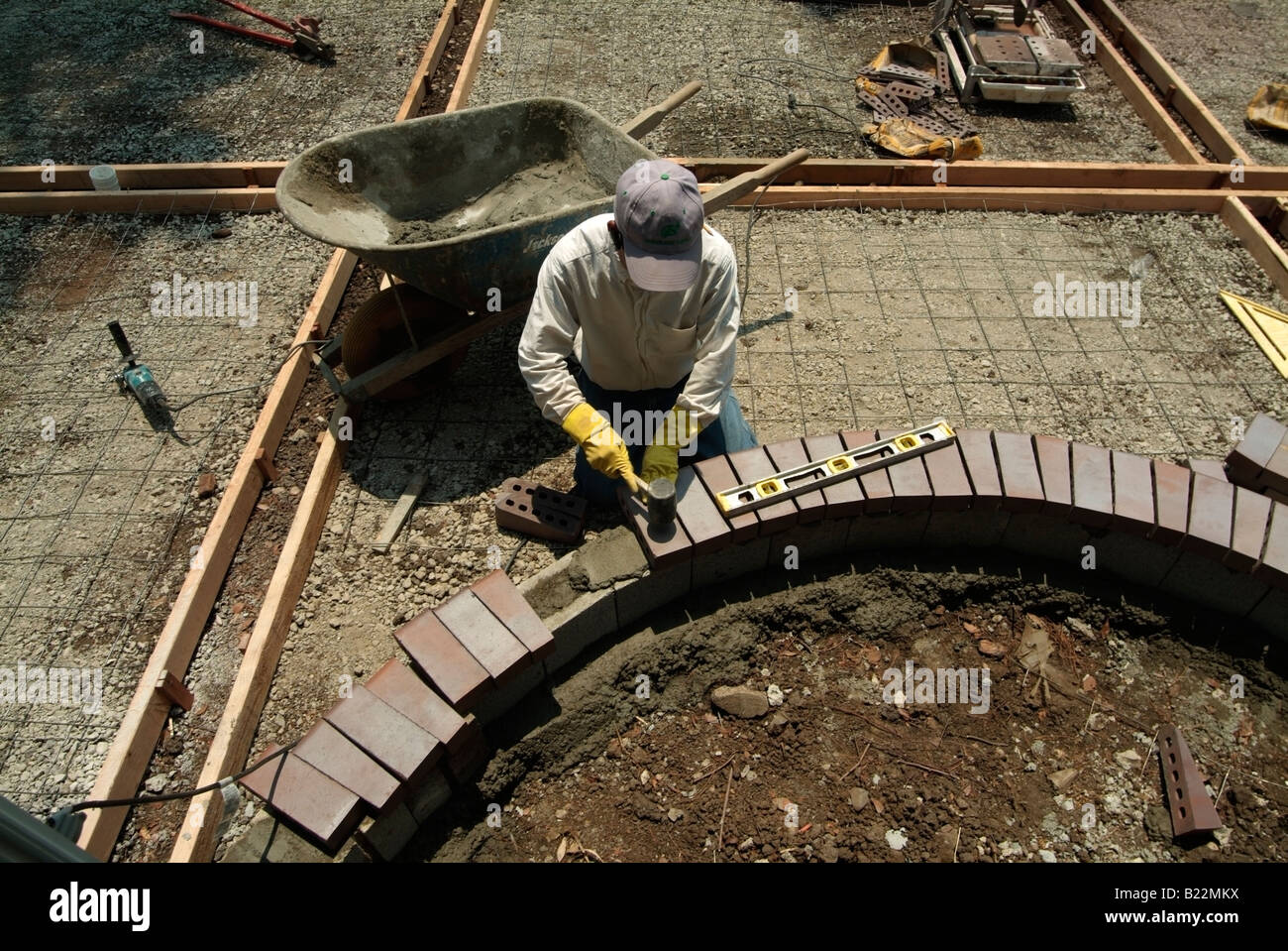 Workman leveling bricks to make a step to a backyard patio in Silicon