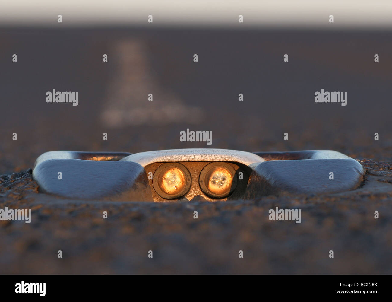 Cats eyes in the middle of the road reflect the sunset at Acol, Kent