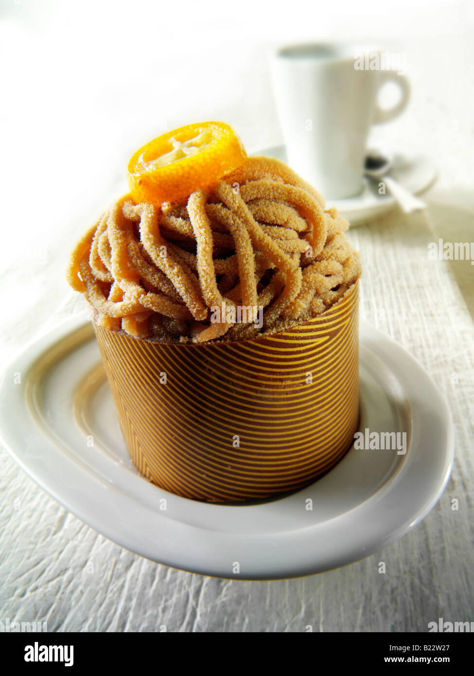 Chocolate shell filled with sponge and chestnut marron puree individual cake with a cup of coffee in a table setting Stock Photo
