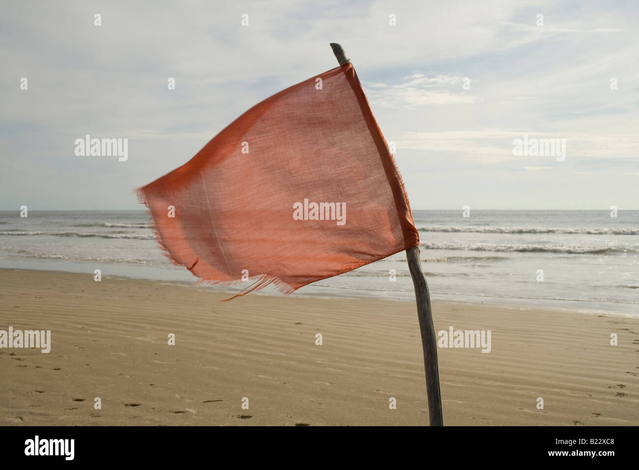 A red flag flies warning of the rip tides along a beach at Cap Skiring, the Casamance, Senegal, West Africa. Stock Photo